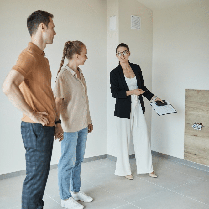 A group of people standing in front of a house with a realtor.